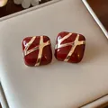 Close-up of vintage red enamel square stud earrings with gold cross pattern - Gold Red