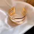Detailed macro shot showing the polished double-layer design of the gold open cuff bracelet - Gold