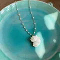 Detail of a conch shell pendant necklace with pearls on a teal ceramic plate. - Conch Pendant Pearl Necklace (2#)
