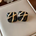 Close-up of vintage black enamel square stud earrings with gold cross design - Gold Black