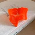 Macro detail of vibrant orange marbled resin bangle with unique twisted geometric design - Bangle / Orange