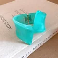 Close-up of a marbled mint green resin bangle with an irregular twisted geometric design. - Bangle / Cyan