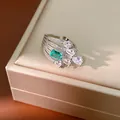Close-up of a silver ring with emerald-cut green stone and pear-shaped zircons - Emerald Green Teardrop Quilted Ring
