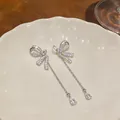Detailed macro shot of elegant silver bow earrings with long sparkling zircon tassels - Bowknot Tassel Style (HE33347) / Silver