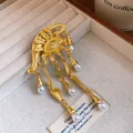 Vista dettagliata di una spilla vintage Evil Eye dorata con eleganti nappe di perle - Oro