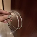 Primo piano dettagliato di orecchini a cerchio argento con strass luccicanti in mano - Perno in Argento Stile Strass Pavé Argento (25#) / Grande / Argento