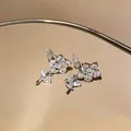 Dettaglio macro di eleganti orecchini a clip a fiore su una superficie dorata riflettente - Stile a Clip / Argento