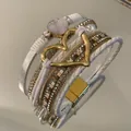 Close-up of white bohemian multi-layer leather bracelet with gold heart and rhinestone - White