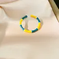 Detailed view of a colorful enamel bamboo-style open ring on satin background. - Yellow And Green (HR3623)