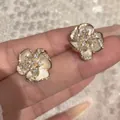 Detailed close-up of French vintage white camellia stud earrings with sparkling stones - Ear Clip - Gold