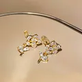Primo piano dettagliato di orecchini a clip a fiore placcati in oro 14k con zirconi - Stile a Clip / Oro