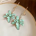 Close-up of elegant mint green enamel flower drop earrings with golden branch stems. - Green