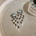 Detailed view of luxury leopard head earrings with pearl tassels and crystal embellishments - Black Panther Pearl Tassel Style / Gold