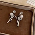 Detailed close-up of silver bow clip-on earrings with elegant white pearl accents - Bow Pearl Style / One Pair / Silver