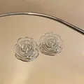 Close-up of silver hollow out rose flower stud earrings with intricate bead edge details - Silver