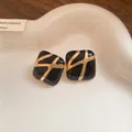 Detailed view of black enamel square stud earrings with elegant gold abstract patterns - Silver Earring Post Style / Black
