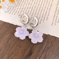 Dettaglio di orecchini a fiore in resina lavanda con perle su un libro vintage - Stile ciondolo a fiore / Viola