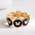 Detailansicht eines elastischen Armbands mit goldenen Schmetterlingsmotiven auf schwarzer Emaille - Gold Butterfly Black Enamel Stretch Bracelet / Schwarz