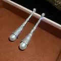 Close-up of long luxury drop earrings with sparkling pavé stones and white pearls - Luxury Water Drop Earrings (HE32973) / Silver