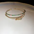Gros plan sur un bracelet jonc double couche en plaqué or 14K avec cœurs et zircons - Or