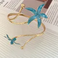 Détail macro d'un bracelet de bras doré orné de motifs d'étoiles de mer en émail bleu - Bleu
