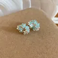 Dettaglio ravvicinato di orecchini a cerchio con fiori in smalto blu e design argentato. - Blu