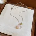 Close-up of a delicate silver chain necklace featuring a pink shell and green zircon pendant. - Shell Star and Green Zirconia Style / Silver