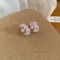 Vista dettagliata di eleganti orecchini a cerchio con fiori in smalto viola su base. - Rosa
