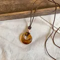 Gros plan d'un pendentif géométrique en résine ambrée sur un collier en cordon marron - Pendentif Rond Irrégulier / 1# Ambre Café