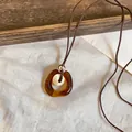 Detail view of a Maillard-style amber resin pendant necklace with soft fabric background. - 6# Amber Coffee