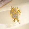 Elegant gold-tone anatomical heart brooch featuring pavé rhinestones and glass drops - Gold