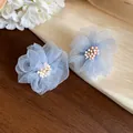Primo piano di eleganti orecchini a lobo a fiore in chiffon azzurro con piccole perline. - Blu