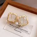 Close-up detail of elegant square gold-toned earrings featuring clear faceted crystals. - Stud Earrings (HE33788) / Gold