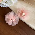 Primo piano di dolci orecchini a lobo a fiore in chiffon rosa con petali delicati. - Rosa