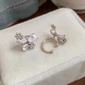 Close-up detail of silver butterfly ear cuffs with zircon flowers on a beige velvet box - Clip-On Earrings / Silver
