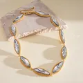 Detailed close-up of a luxury marquise-cut crystal necklace on a textured stone riser - White