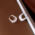 Primo piano di orecchini a U in argento con trama metallica stropicciata unica - Argento
