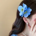 Détail d'une élégante pince à cheveux fleur en tissu bleu sur cheveux bruns ondulés - Pinces à cheveux bec de canard / 1 Pièce / Bleu