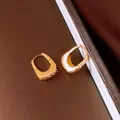 Primo piano di orecchini a U placcati in oro 18 carati con trama metallica stropicciata - Oro