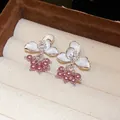 Detailed close-up view of elegant white enamel flower stud earrings with purple pearl charms - Purple and White