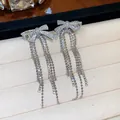 Detailed view of elegant silver-tone bow tassel earrings with sparkling zircon inlay - Bow Tassel / Silver