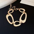 Close-up of golden chunky bracelet with irregular oval hollow links and adjustable chain. - Bracelet / Gold