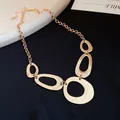 Detail view of a chunky gold-tone necklace with irregular geometric oval pendants. - Necklace / Gold