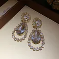 Close-up detail of luxurious water drop earrings with shimmering crystal rhinestones. - Top Round Bottom Water Drop Style / Gold