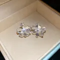 Dettaglio di orecchini a lobo a fiore scintillanti con petali testurizzati in scatola. - Argento