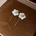 Elegant white shell flower earrings with 18k gold plating details on a brown velvet box - Gold