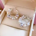 Vue détaillée de boucles d'oreilles créoles avec perles et zircons dans une boîte à bijoux. - Gris Café