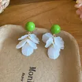 Gros plan de puces d'oreilles vertes avec glands en pétales d'acrylique blanc sur plateau - Style Gland à Pétales avec Tige Argent / Vert et Blanc