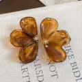 Detail view of brown marbled resin flower earrings with gold center accents. - Coffee