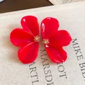Macro view of oversized red resin flower stud earrings with detailed golden stamen - Red